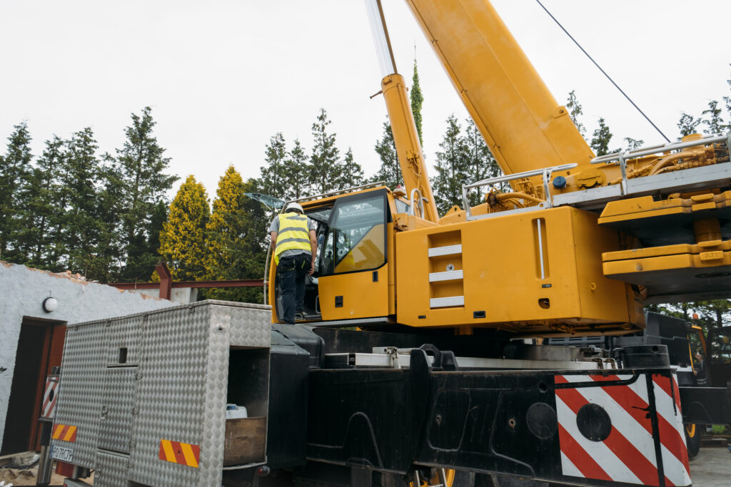 Maschinenführer klettert auf einen Baukran, der schwere Fracht hebt.